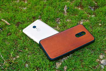 Smartphone & Back Cover On Green Grass Background Close Up.