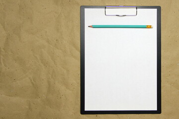 A tablet with a white sheet of A4 format on a beige craft paper.