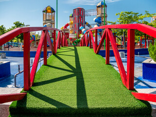 Bridge covered with artificial grass leading to a children's playground, in Children's World Park, Bucharest.