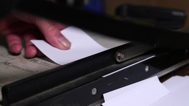 close up of a hand guillotine cutting white paper.