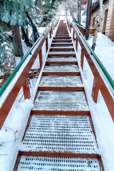 Focus on stairs with grate treads and metal handrails against snow covered hill