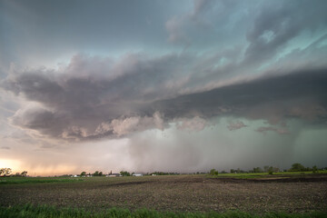 A severe storm rains heavily on the flat farmland of the great plains at sunset.