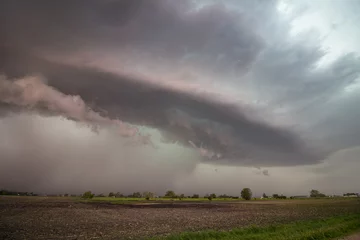 Fotobehang A supercell thunderstorm hovers over a flat landscape, dropping rain and hail. © Dan Ross