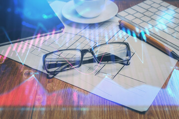 Financial chart hologram with glasses on the table background. Concept of business. Double exposure.