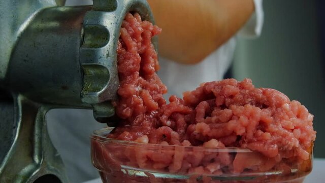 Cooking minced meat with a manual meat grinder. Close-up of front part of mincing-machine with mincemeat in. Showing the forcemeat process.