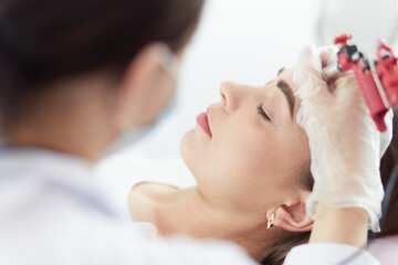 A young girl having red lips permanent makeup, micropigmentation
