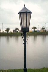 A vintage metal black lamp post with lake and nature background