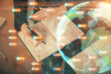 Double exposure of hands making notes with world map hologram and data theme icons. Concept of global computer data.