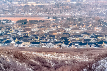 Houses in Alpine Utah neighborhood amid snowy hill and abundant trees in winter