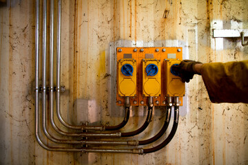 Miner electrician worker hand wearing a glove inspecting internal wall outlet power point switch...