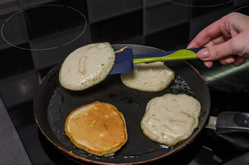 Pancakes are fried in a pan on an induction stove	
