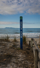 Beach access sign looking at waves on a beautiful summer beach