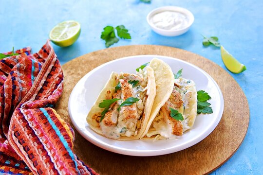 Tacos with chicken, cabbage salad and sour cream sauce in a wheat tortilla