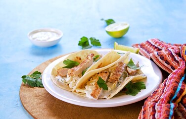Tacos with chicken, cabbage salad and sour cream sauce in a wheat tortilla