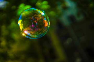 Colored iridescent soap bubble in the air. On blurred background