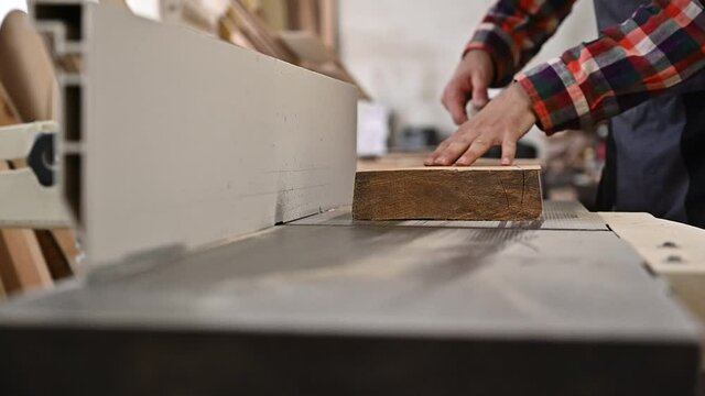 Working process in the carpentry workshop.A man in overalls uses sthicknessing planer machine in a carpentry workshop.Profession, carpentry, woodwork and people concept