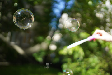 Soap bubble in the air. Girl makes soap bubbles with a stick in her hand.