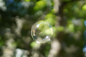 Soap bubble in the air with reflections. On blurred background