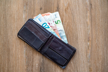 Old shabby wallet with euro money on a wooden background