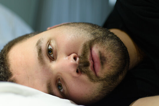 man lying on bed staring into the camera