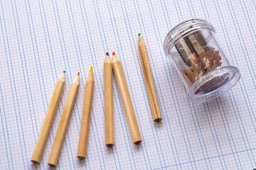 Back to school. Vintage wooden simple pencils on squared paper. On the side is a pencil sharpener.