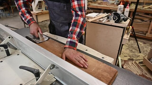 Working process in the carpentry workshop.A man in overalls uses sthicknessing planer machine in a carpentry workshop.Profession, carpentry, woodwork and people concept