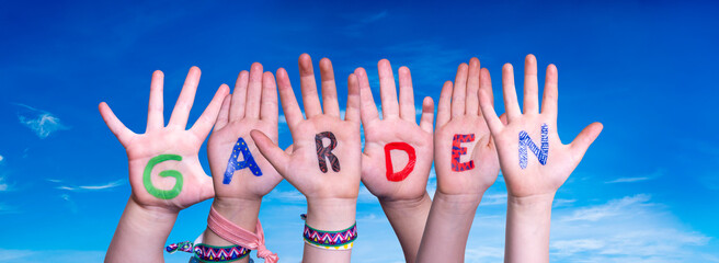 Children Hands Building Colorful English Word Garden. Blue Sky As Background