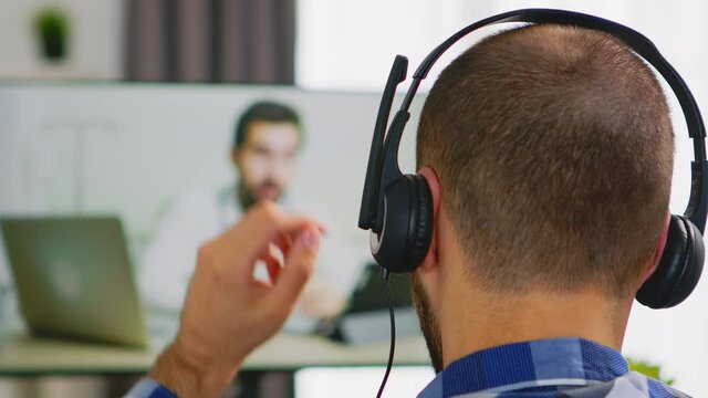 Man with headphones during online consultation with doctor. Handicapped invalid paralysed person, alone at home, depression and health problems, pensive, sad and unhappy man