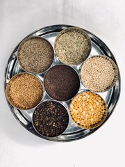 Black pepper, Mustard seeds, cumin seeds, Fenugreek seeds, Urad dal, Split chick peas spices kept in a round steel bowl