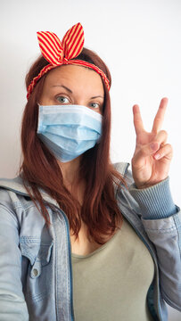 Woman With A Medical Mask And A Striped Headband - Hand Gesture V Sign For Victory Or Peace.