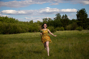 Obraz premium Young smiling girl with her hair down running barefoot on the grass