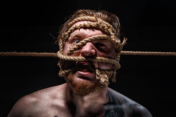 Photo of binded bearded man with rope on face