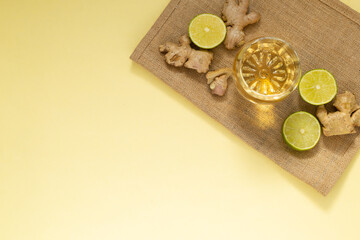 glass of cold tea with three lemon slices and pieces of ginger on a blue background, minimalist