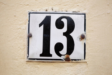 Weisses Hausnummernschild Dreizehn auf heller  Hauswand, Deutschland, Europa