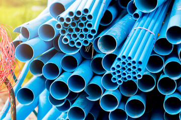 Selective to blue plastic pipe background. PVC pipes stacked in warehouse of construction site. ...