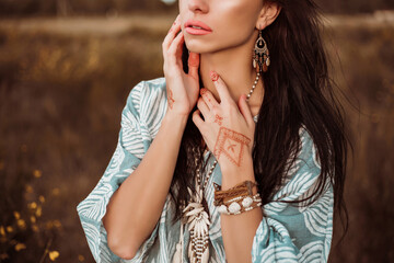 Dramatic portrait of a beautiful lady, outdoors, holding a mehendi drawing, bright makeup, bracelets, accessories, boho style, shirt, jeans © Nabokov Alex