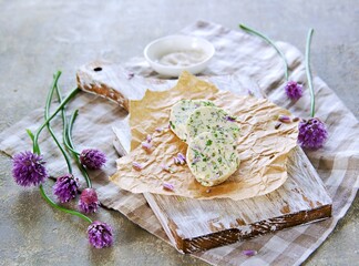 Sliced washers herbs butter with garlic, dill and chives flowers on a wooden board