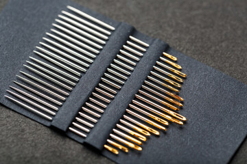 A set of sewing needles on a black background.