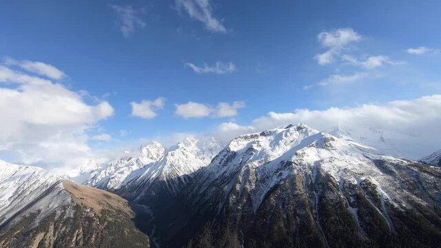 4k timelapse video of the current of clouds and changing weather in the mountains in spring green gorge and snow-capped mountain tops