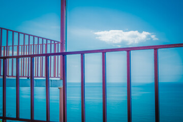 Metal grille fencing against the blue sky. Observation terrace on a background of blue sea. Playground in a mountain hotel. Spring. Georgia.