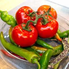 Red tomatoes on a branch and hot green pepper.