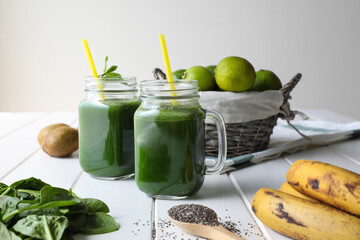 healthy and natural green smoothie made of fresh ingredients kale, lime kiwi and chia seeds on a white wooden table