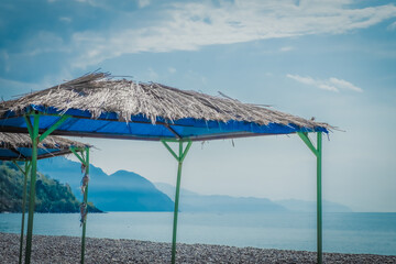 View of the beach area. Sun umbrellas against the backdrop of the sea and mountains. Empty coastline. Evening. Georgia.