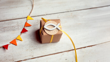 Kommunion, Konfirmation, Firmung, Taufe, Glaube - kleines Geschenk mit gelbem Band auf hellem Holz...