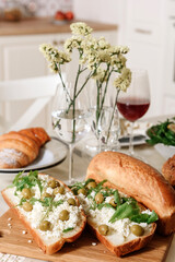 Sandwiches with curd cheese and olives on a served table.