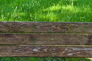 Naklejka premium old wooden plank bench on a background of green grass