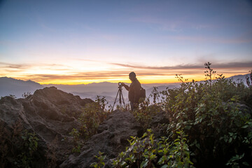 A Photographer in action during sunrise in the mountains