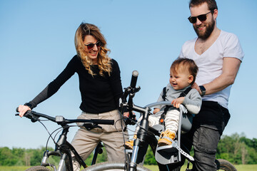 Obraz premium Parents on bikes looking down at their jolly adorable son.