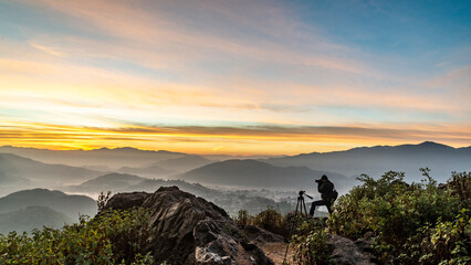 A Photographer in action during sunrise in the mountains