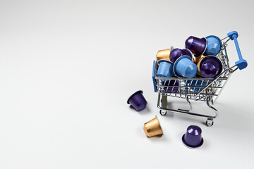 Caffeine, hot drinks and objects concept. Close up blue, purple and golden capsules or pods for coffee mashine in shopping cart on white isolated background. Top view with copyspace. Selective Focus.